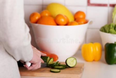 年轻的白人妇女正在切黄瓜。