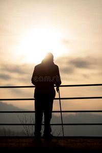 老人拄着拐杖站在夕阳下照片