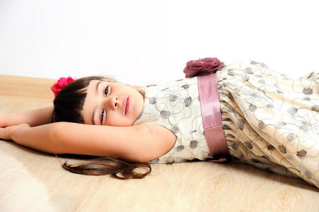 漂亮的微笑女孩躺在家里的地板上。