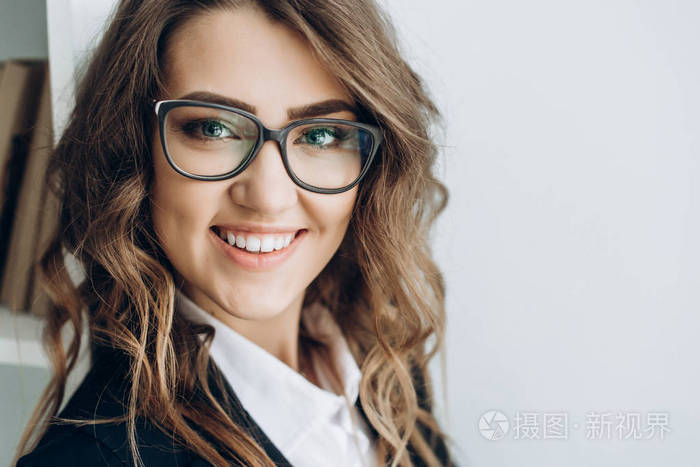 一位穿西装戴眼镜的迷人的积极商业女性的肖像