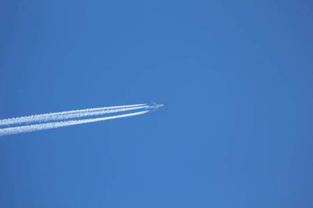 蓝天上的一架飞行飞机，天空中凝结的痕迹。