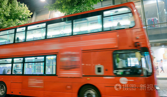 红色公共汽车沿着伦敦英国的城市街道加速行驶。