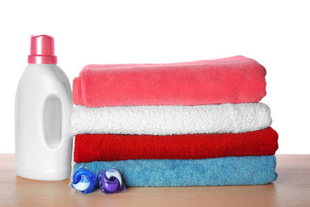 折叠毛巾和洗衣清洁剂在桌反对白色背景
