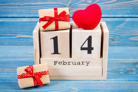日期2月14日在立方体日历, 包裹礼物和红色心脏, 情人节装饰照片