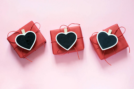 情人节作文 三红色礼品盒与夹作为在黑板上的文字在粉彩粉红色背景的空间。从上面查看