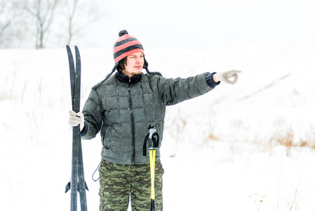 快乐活跃的年轻白种滑雪者在一个滑稽的帽子外面下雪的天气 poiting 他的手指