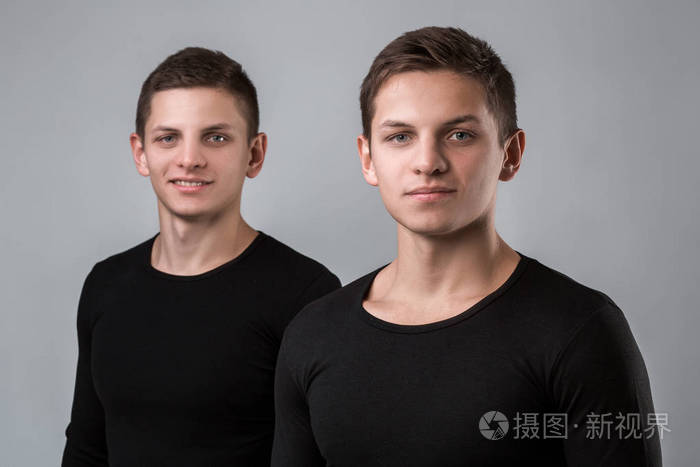 两个双胞胎兄弟站在灰色的背景