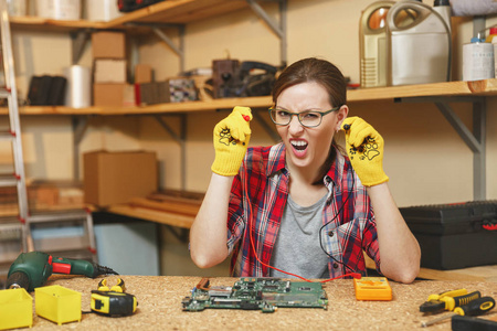 电工用万用表。漂亮的年轻女子在黄色手套, 眼镜数字电子工程师维修, 焊接计算机 Pc 主板在车间在不同的工具木桌