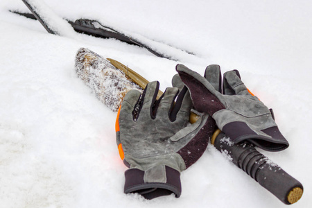 雪刷和冬天手套在雪覆盖的汽车引擎盖特写镜头