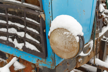 冬季被雪覆盖的旧拖拉机特写镜头的主前大灯