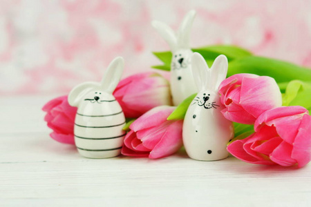 复活节兔子和一束粉红色郁金香在白色的木制背景上。 复制空间