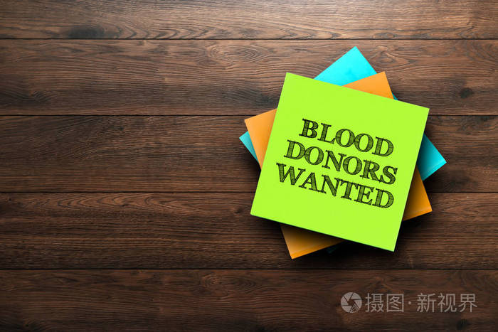 献血者想要的短语写在棕色木制背景上的多色贴纸上。 医学概念战略计划规划。