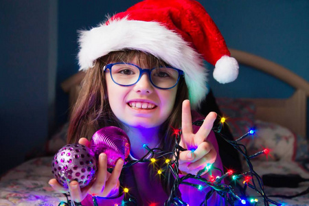 戴着圣诞帽和圣诞灯的小女孩做个好手势