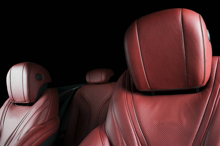 现代豪华车里面。高档现代汽车内饰。舒适的真皮座椅。红色穿孔皮革驾驶舱与孤立的黑色背景。现代汽车内饰细节