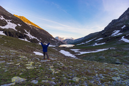 一个人看着五颜六色的日出在阿尔卑斯山高。广角视野从上面与发光的山峰在背景。夏季探险与探索