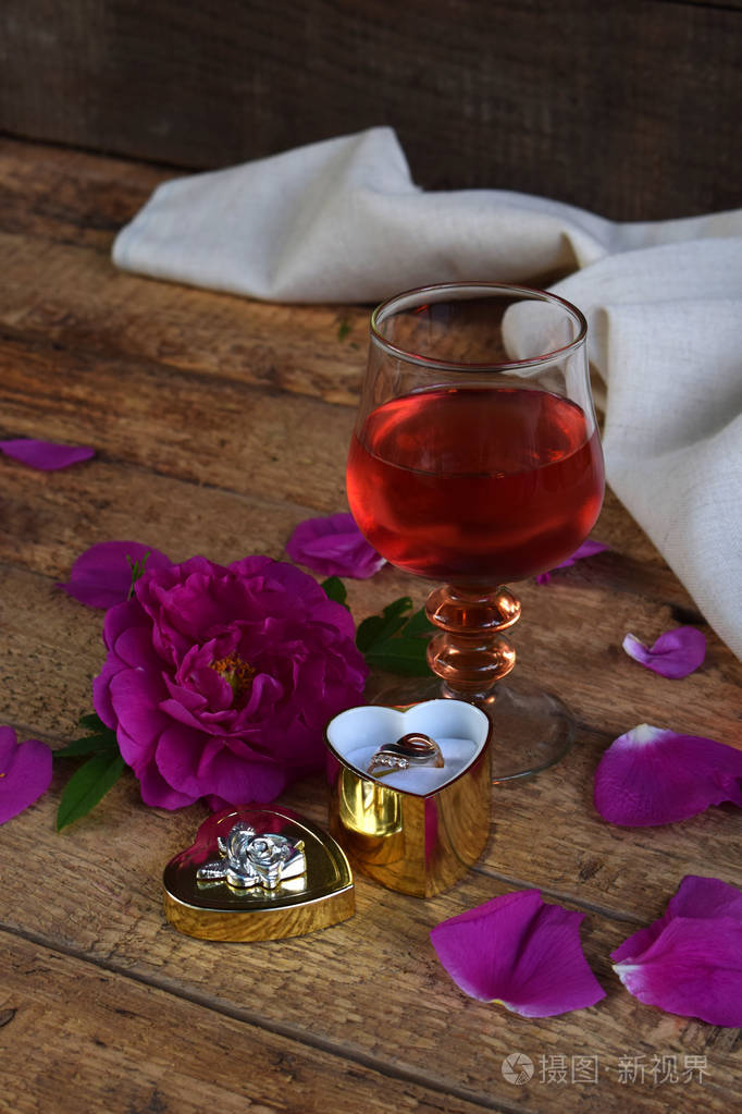 一杯红葡萄酒, 玫瑰和乡村木桌上的戒指.