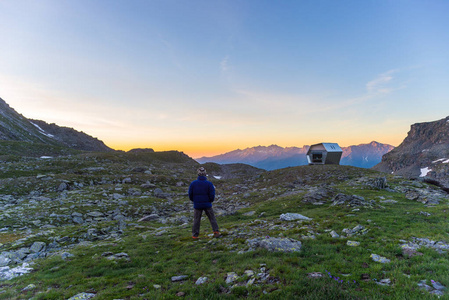 一个人看着五颜六色的日出在阿尔卑斯山高。广角视野从上面与发光的山峰在背景。夏季探险与探索