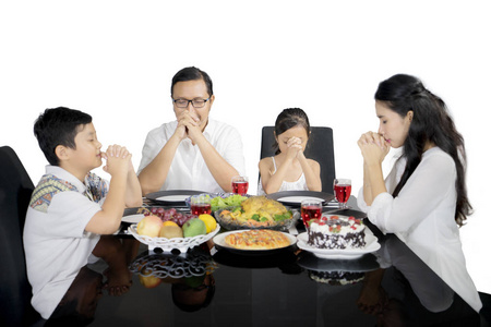 基督教家庭在工作室吃饭前祈祷基督教少女手里拿着圣经.