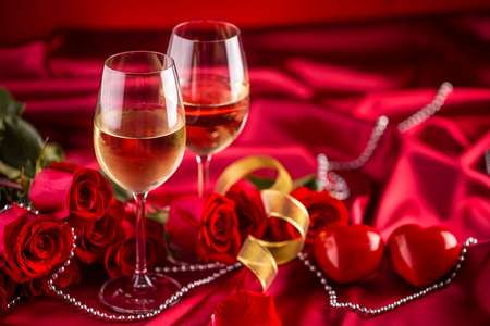 情人节或婚礼的概念。红酒杯红玫瑰和浪漫的设置为两个红色。贺禧或周年贺卡