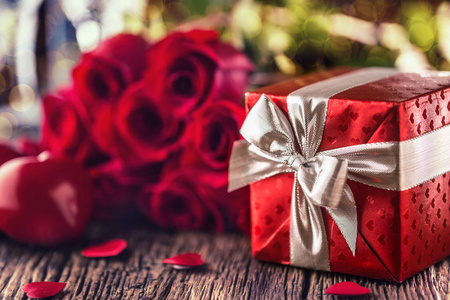 情人节婚礼的概念。玫瑰花束和红色的心在木桌上包裹的礼物