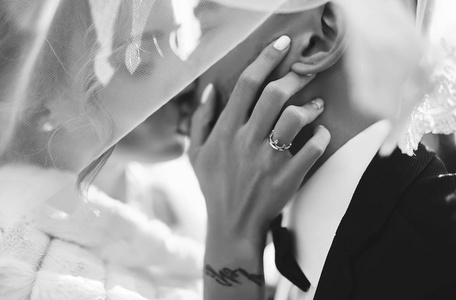 新娘和新郎在飞扬的面纱的阴影下温柔地亲吻.美丽的照片.伙计们喜欢.