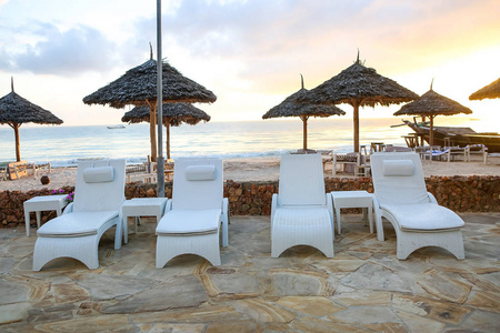 海滩与太阳躺椅和休息在日落的地方。一个美丽