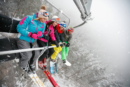 愉快的朋友滑雪者和滑雪在高山滑雪缆车