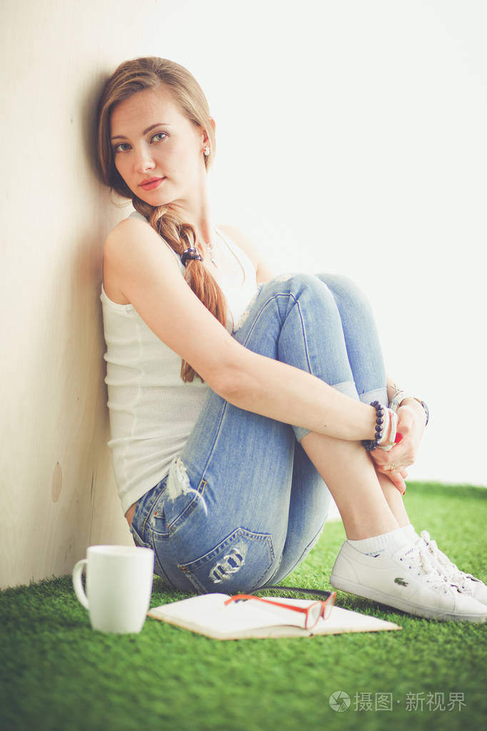 美丽的女人坐在地板上,捧着一杯.美丽的女人