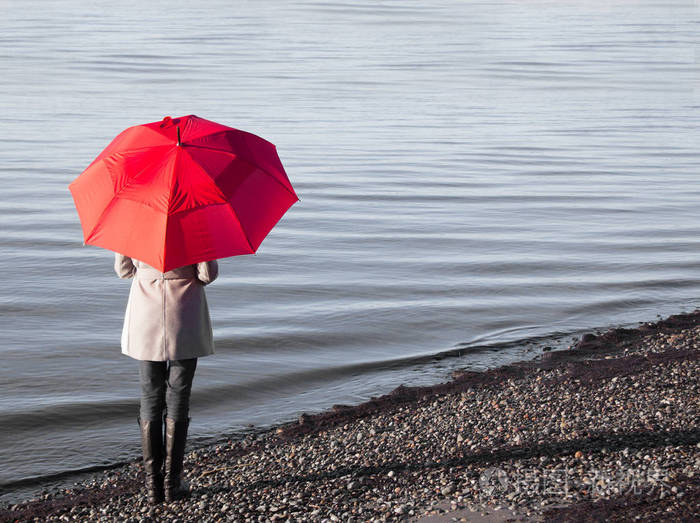 海滩上的女人带着一把红色的雨伞