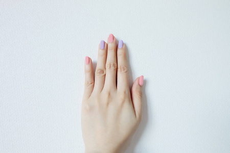 关闭指甲油指甲修剪。 美丽的女人是手在粉红色和紫罗兰色粉彩在白色背景伟大的任何用途。