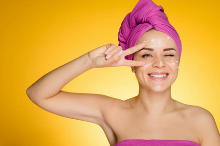 女人用毛巾在她的头上摘下白色的面具, 在黄色的背景微笑