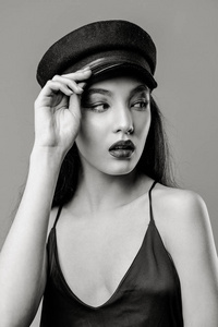 黑白肖像，华丽的年轻时尚模特戴帽子摆在工作室背景上