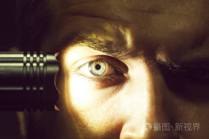 年轻男性长着毛茸茸的眉毛严肃的脸用手电筒在演播室特写镜头上照明