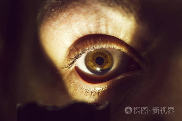 年轻男性长着毛茸茸的眉毛严肃的脸用手电筒在演播室特写镜头上照明