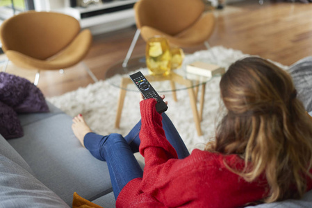 一个女人在家里度过一个轻松的周末和看电视的高角度镜头.照片