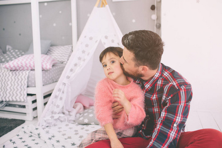可爱的小女儿和她英俊的年轻爸爸一起在孩子的房间里玩耍。爸爸和孩子坐在卧室的地板上一起度过时光