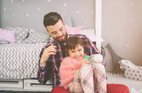 可爱的小女儿和她英俊的年轻爸爸一起在孩子的房间里玩耍。爸爸和孩子坐在卧室的地板上一起度过时光