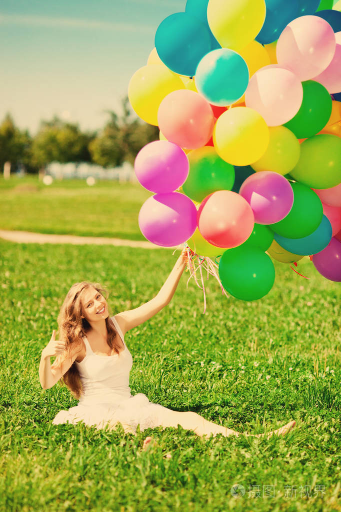 生日快乐的女人,手里拿着彩虹色的气球.阳光和积极的自然能量.
