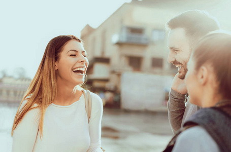 建筑的朋友在一个阳光明媚的日子里,三个快乐的朋友在街上聊天,背景是