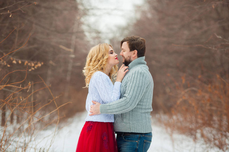 在寒冷的天气里，美丽的年轻夫妇穿着轻便的毛衣在公园里散步
