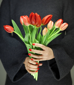 女人手拿着完美的指甲艺术，手拿着红色的春天花朵，郁金香，感官工作室的镜头，可以作为背景。