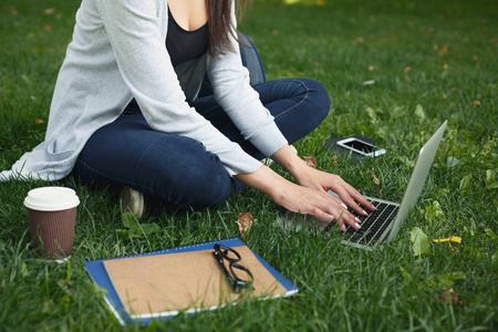 在公园里使用笔记本电脑的年轻沉思的妇女