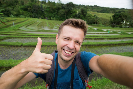 愉快的白种人背包旅行在米种植园和显示拇指