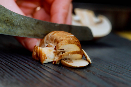 蘑菇片和欧芹片上面有一把刀，在厨房里切蘑菇的木板上