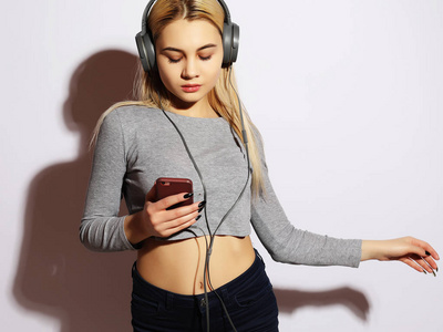 快乐的年轻女子听音乐从智能手机超过白色