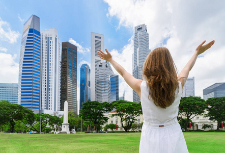 在新加坡市中心的草坪上举起双臂的女孩