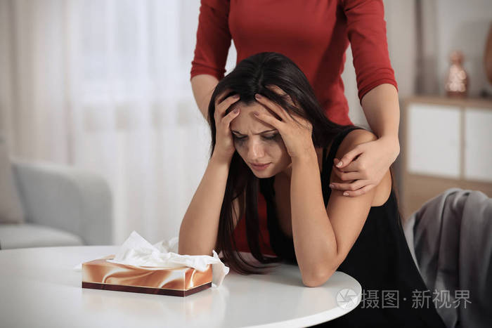 年轻的女人在室内安慰她的朋友