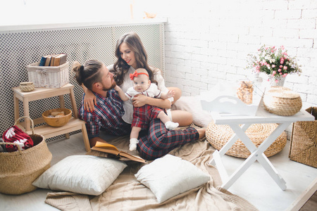 快乐的年轻家庭的母亲, 父亲和女儿在家里玩地毯