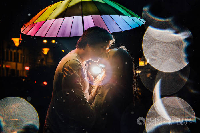 一对年轻的情侣在夜晚的伞吻下在城市街道照片-正版商用图片10zun1-摄图新视界