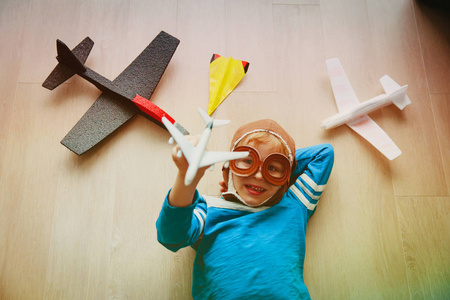 带头盔和眼镜玩玩具飞机的快乐小男孩